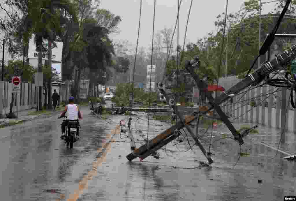 A man on a motorcycle rides past fallen power lines in the aftermath of Hurricane Fiona in Higuey, Dominican Republic, Sept. 19, 2022.