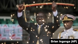 Le nouveau président kenyan William Ruto, vu derrière des feux d'artifice de fontaine, tient une épée de cérémonie alors qu'il prête serment lors d'une cérémonie qui s'est tenue au stade Kasarani de Nairobi, au Kenya, le 13 septembre 2022.