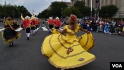 Bailarina colombiana en movimiento mientras sale a la puerta de inicio del desfile en la Constitution Avenue en Washington DC.  (Foto VOA / Tomás Guevara)