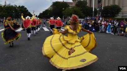 Bailarina colombiana en movimiento mientras sale a la puerta de inicio del desfile en la Constitution Avenue en Washington DC. (Foto VOA / Tomás Guevara)