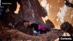 Una niña centroamericana cruza el muro entre México y Estados Unidos a través de un agujero.