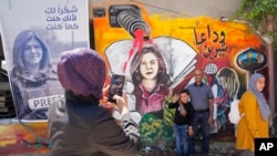 FILE - Palestinians visit the site where Al Jazeera journalist Shireen Abu Akleh was shot and killed, in the West Bank city of Jenin, May 18, 2022.