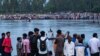 In this picture taken on Sept. 25, 2022, people gather along the banks of the Karatoya River after a boat capsized near the town of Boda in Bangladesh. A day later, rescue workers recovered seven more bodies.