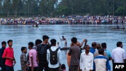 In this picture taken on Sept. 25, 2022, people gather along the banks of the Karatoya River after a boat capsized near the town of Boda in Bangladesh. A day later, rescue workers recovered seven more bodies.