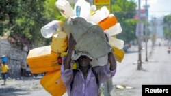 A man carries containers to fill with water amid water shortages due to daily protests against high gasoline prices and crime, and to stock up for Storm Fiona approaching in the Caribbean region, in Port-au-Prince, Haiti. Sept. 17, 2022.