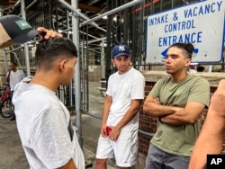 FILE — Axel Coronado, center, listens to a conversation between brothers Leonardo Oviedo, left, and Angel Mota, Aug. 10, 2022, in New York. Coronado has been staying at a New York City shelter after fleeing Venezuela to escape his country's regime and to seek a better a life in the United States.