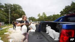 Victoria Colson, de 31 años, de Tampa, carga bolsas de arena en su camioneta junto con otros residentes de Tampa que esperaron unas dos horas en Himes Avenue Complex para llevarse sus 10 bolsas gratis, el domingo 25 de septiembre de 2022 en Tampa, Florida. (Luis Santana/Tampa Bay Times vía AP)