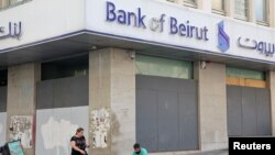 FILE - A man sits by a closed Bank of Beirut branch in Beirut, Sept. 20, 2022. 