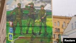 A man smokes while walking past a mural, which was painted on a multi-storey building in support of the Russian army, in Moscow, Sept. 21, 2022. 