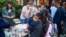 A woman, part of a group of immigrants who had just arrived, holds a child as they are fed outside St. Andrews Episcopal Church, Sept. 14, 2022, in Edgartown, Massachusetts, on Martha's Vineyard.
