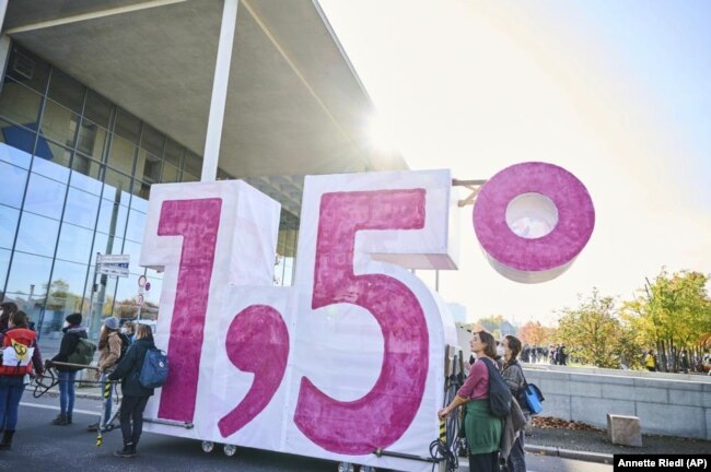 FILE - Demonstrators from Extinction Rebellion push a cart in the shape of the climate target "1.5" in Berlin, Germany on October 24, 2021. (Annette Riedl/dpa via AP, File)