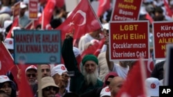 FILE - Demonstrators hold banners that read, "Law for the development of the spirit and moral" and "LGBTQ, remove your dirty hand from our children" during an anti LGBTQ protest in Fatih district of Istanbul, Sept. 18, 2022.