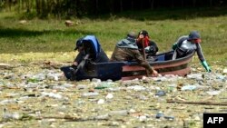 People collect waste of plastic residues, glass and other materials at the Cerron Grande reservoir in Potonico, El Salvador, on Sept. 9, 2022.