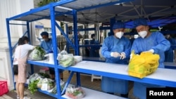 FILE - Workers in protective suits prepare to deliver food to those inside a residential compound, amid a lockdown to curb the coronavirus disease outbreak in Chengdu, Sichuan province, China, Sept. 2, 2022.