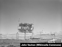 A 1940 photograph of a signpost at Wounded Knee. Sacred Heart Catholic Church, in the background, burned down during the 1973 AIM takeover.