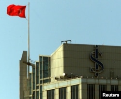 FILE - A Turkish flag waves from the top of the skyscraper housing Turkey's leading private bank, Is Bankasi, next to the bank's blue logo resembling a dollar sign, in Istanbul's financial district, May 1, 2001.