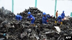 Des travailleurs rassemblent des tas de ferraille d'aluminium et de métaux automobiles pour les recycler à l'usine Romco de Lagos, le 26 août 2022.