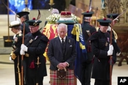 Raja Inggris Charles III, tengah, dan anggota keluarga kerajaan lainnya berdiri di dekat peti mati Ratu Elizabeth II di Katedral St Giles, Edinburgh, Skotlandia, Senin 12 September 2022. (Foto: via AP)