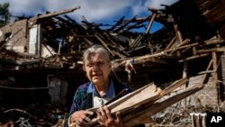 Una mujer recopila leña para calentarse en una escuela destruida que sirvió de base a las fuerzas rusas, en una zona recuperada recientemente por el ejército ucraniano a las afueras de Izium, Ucrania, el 19 de septiembre de 2022. 