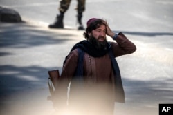 A shocked Taliban fighter stands guard at the explosion site, near a mosque, in Kabul, Afghanistan, Sept. 23, 2022.