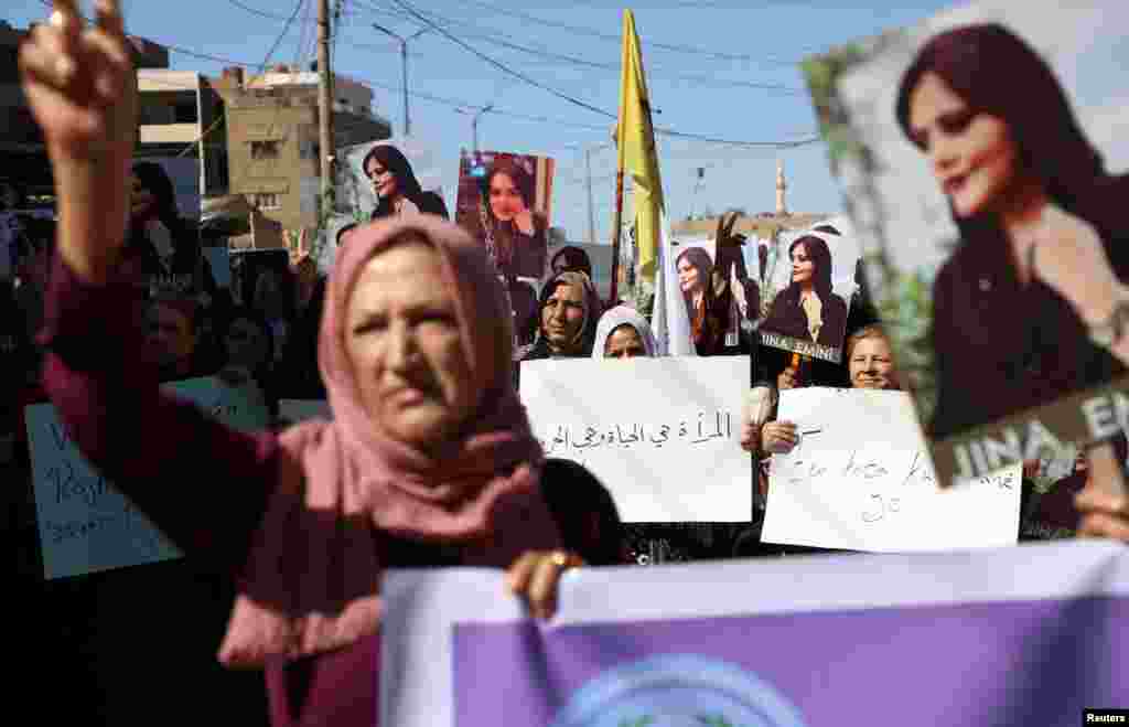 Women carry banners during a protest over the death of 22-year-old Mahsa Amini in Iran, in the Kurdish-controlled city of Qamishli, northeastern Syria Sept. 26, 2022.