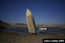 A formerly sunken boat, upright along the shoreline at the Lake Mead National Recreation Area, June 10, 2022, (AP Photo/John Locher, File)