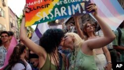 FILE - Two women kiss as they hold up a placard that reads in Turkish: "I live free. Who's the fool who will put me in chains? I would be shocked" during the LGBTQ Pride March in Istanbul, Turkey, June 26, 2022.