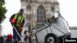 A cleaner sweeps a street outside Westminster Abbey, following the funeral of Britain's Queen Elizabeth, in London, Sept. 20, 2022. 