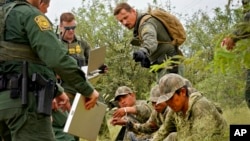 Apprehended migrants are processed by U.S. Border Patrol agents in the desert brush at the base of the Baboquivari Mountains, Sept. 8, 2022, near Sasabe, Ariz. The desert region located in the Tucson sector just north of Mexico is one of the deadliest stretches along the international border.