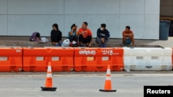 Migrants sit on a sidewalk at the City of San Antonio Migrant Resource Center in Texas, where two planeloads of mostly Venezuelan migrants sent via Florida to Martha’s Vineyard in Massachusetts had originated, Sept.16, 2022. 