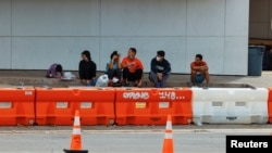 미국 텍사스주 샌안토니오 시내 이주자 지원 시설 앞 도로에 남부 국경을 넘어온 사람들이 앉아 있다. (자료사진)