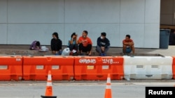 Sejumlah migran duduk di pinggir jalan di dekat Pusat Informasi Migran di San Antonio, Texas, pada 16 September 2022. (Foto: Reuters/Jordan Vonderhaar)