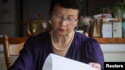 FILE - Sophie Luo Shengchun, the wife of jailed Chinese human rights lawyer, Ding Jiaxi, reads a letter from him at her home in Alfred, New York, July 28, 2022.