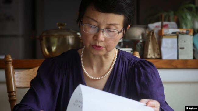 资料照片：2022年7月28日，被监禁的中国人权律师丁家喜的妻子罗胜春在纽约州阿尔弗雷德的家中阅读丁家喜的一封信。（路透社照片）