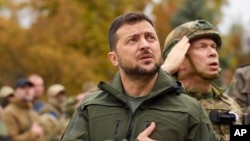 In this photo provided by the Ukrainian Presidential Press Office, President Volodymyr Zelenskyy sings the Ukrainian national anthem during his visit to the city of Izium, Kharkiv region, Sept. 14, 2022.