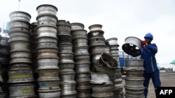 Un homme essaie d'organiser des tas de roues de ferraille pour les recycler à l'usine Romco de Lagos, le 26 août 2022.