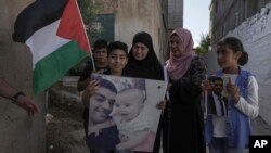 Family members of Palestinian Mohammed Abu Kafieh pose with his photos at his family house in the West Bank village of Beit Ijza, Sept. 25, 2022 a day after he was shot and killed by Israeli forces in what Israeli army claimed was a ramming attack.