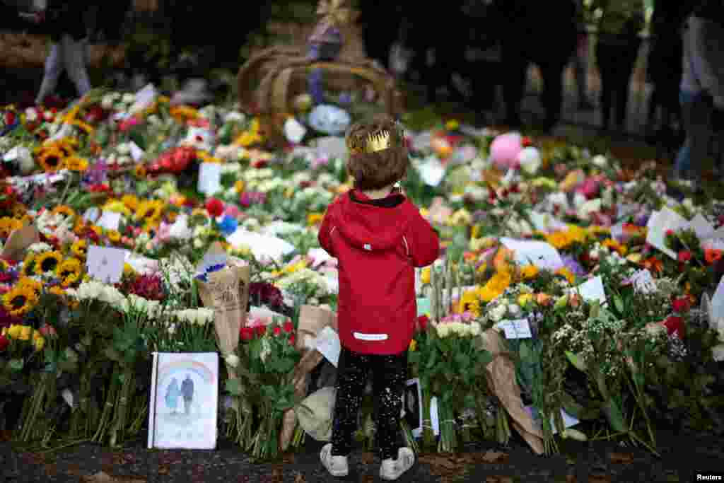 A child wearing a cardboard crown looks at floral tributes in Green Park, following the death of Britain&#39;s Queen Elizabeth, near Buckingham Palace in London.