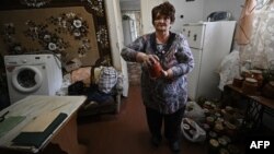 This photograph, taken Sept. 16, 2022, shows Lubov, 69, holding fruit jars recovered from the cellar of her water-damaged home in Kryvyi Rih, where dozens of homes were flooded after a Russian attack damaged a dam upstream, Sept. 14, 2022.