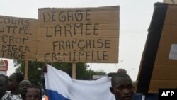 FILE: A man holds a placard reading "Clear off criminal French army" as people demonstrate against French military presence in Niger on September 18, 2022 in Niamey.