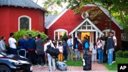 Los inmigrantes se reúnen con sus pertenencias frente a la Iglesia Episcopal de St. Andrews, el miércoles 14 de septiembre de 2022, en Edgartown, Massachusetts.