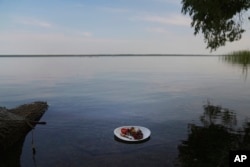 Elaine Fleming, a Leech Lake Band of Ojibwe elder, offers a plate of harvested foods, including wild rice, venison and berries all sprinkled with tobacco, to the waters of Leech Lake after a day of wild rice harvesting and processing, in Cass Lake, Minnes
