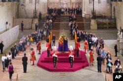 Warga Inggris memberikan penghormatan di sekitar peti mati Ratu Elizabeth II di Westminster Hall, London, 14 September 2022, di mana Ratu akan disemayamkan sebelum pemakamannya pada 19 September. (Foto: via AP)