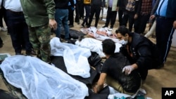FILE - A man is comforted as he sits next to the body of a loved one who was killed in terrorist bombings in Kerman, Iran, on Jan. 3, 2024. A U.S. official says the United States government warned Tehran that an attack was planned.