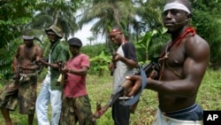 FILE- Militants stand guard at Okorota, near Port Harcourt, Nigeria. Nigeria's government resumed paying stipends to former militants in August 2016, even as security forces reported killing scores of fighters disrupting petroleum production in the oil-rich Niger Delta. 