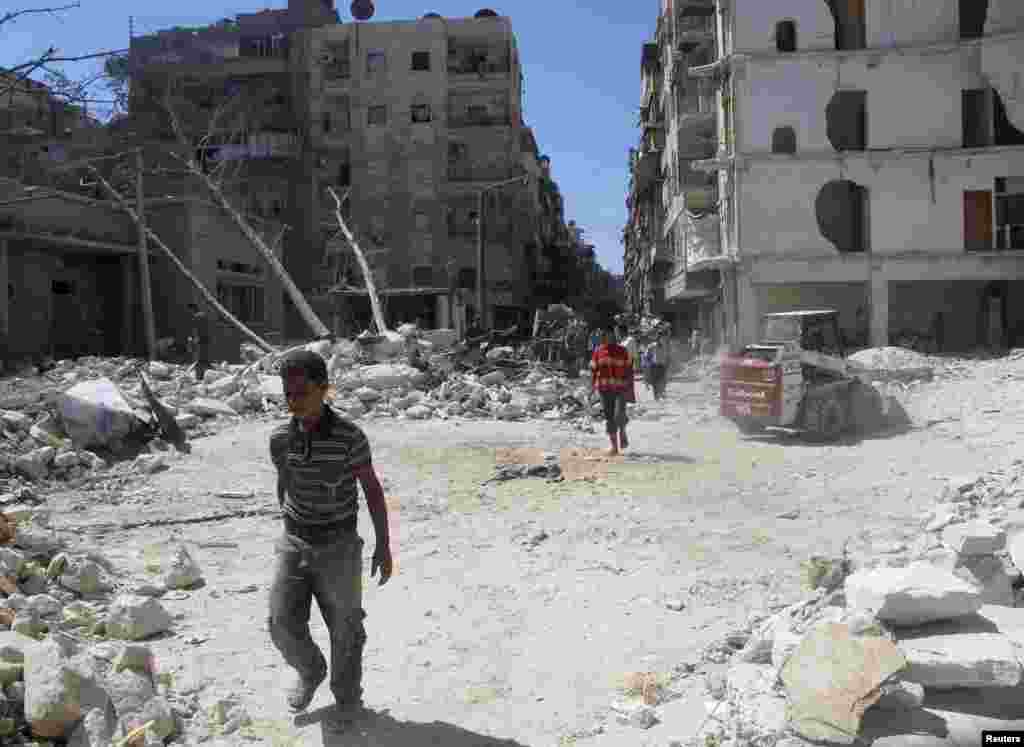 People walk on rubble of buildings damaged by what activists said was shelling by forces loyal to Syria's President Bashar al-Assad in Aleppo's Bustan al-Qasr district, Sept. 9, 2013. 