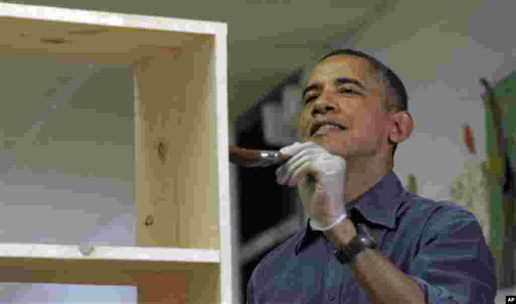 President Barack Obama stains a bookshelf at Burrville Elementary School as the first family participated in a community service project for the National Day of Service, part of the 57th Presidential Inauguration, in Washington, January 19, 2013.