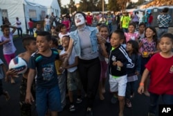 A woman performs as a mime for Central American migrant children at the Jesus Martinez stadium in Mexico City, Tuesday, Nov. 6, 2018.