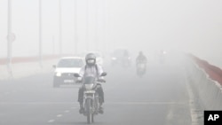 FILE - Motorists drive surrounded by smog, in New Delhi, India, Nov. 8, 2017.