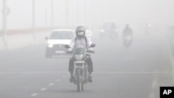 FILE - On a November day in 2017, motorists in New Delhi drive surrounded by smog. A thick, gray haze enveloped India's capital as air pollution hit dangerous levels. (AP Photo/Altaf Qadri)